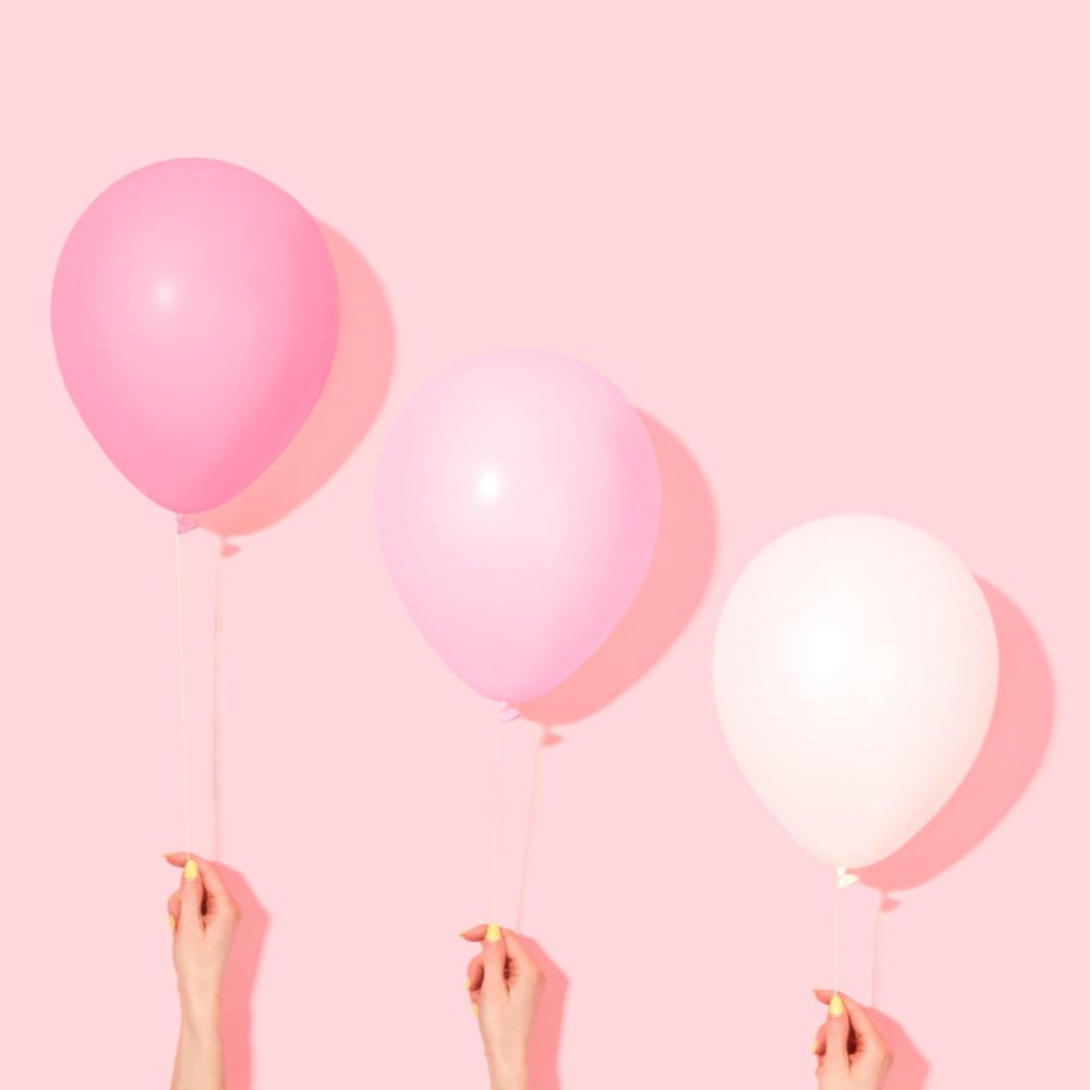 Three pink balloons arranged at varying heights on a pink background