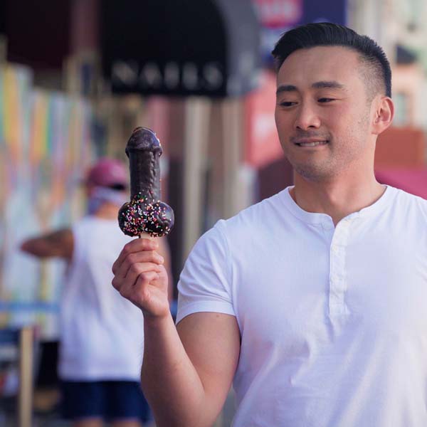 Man looking at penis-shaped ice cream with desire.