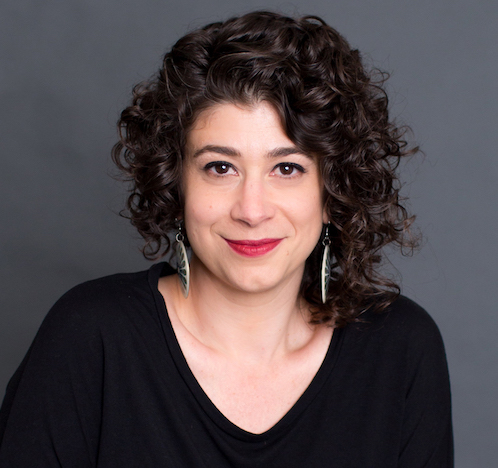 Headshot of a woman with curly brown hair, brown eyes, wearing a black shirt