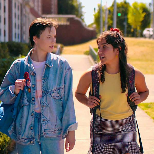 Two high-school age people walking towards the camera in conversation.