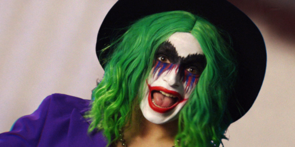 A person dressed as the Joker. They are smiling wide and looking into the camera.