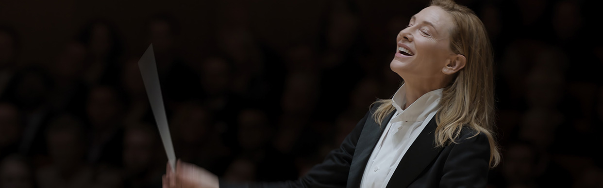 Film still of Cate Blanchett portraying Lydia Tár, the first woman chief conductor of the Berlin Philharmonic, conducting the orchestra.