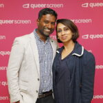 Two people in front of a pink background