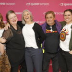 Five people in front of a pink background