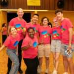 A group of MGFF24 volunteers in pink MGFF24 merch. They are posing together and smiling at the Program Launch Party.