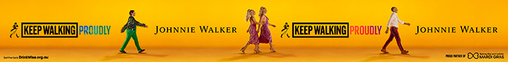 Johnnie Walker advertising. Text reads: Keep Walking Proudly. Image shows four people full height walking from the left side of the banner to the right side of the banner in a gold room. The text is repeated between each person.