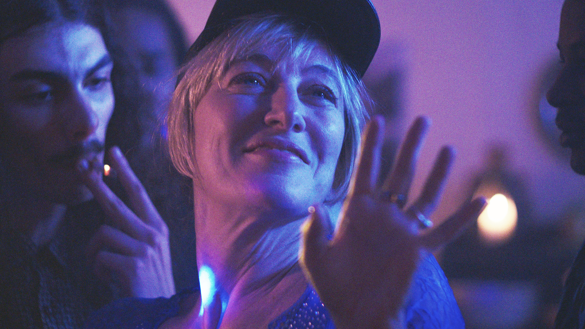 A woman in a baseball cap dances amongst a group of people