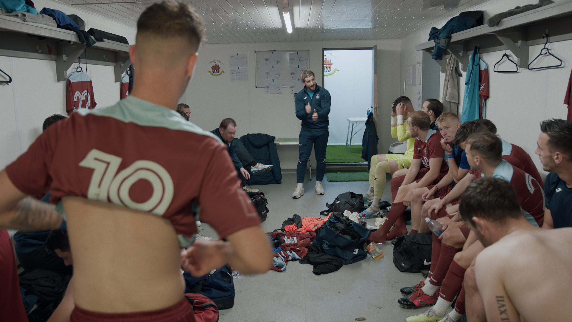 A group of men sit around in a soccer changing room