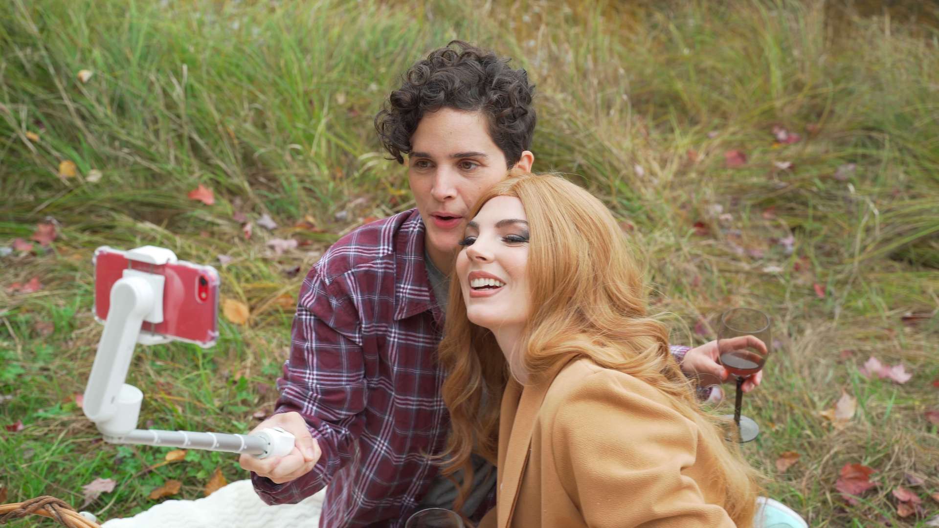 On a picnic blanket, two people pose for a selfie