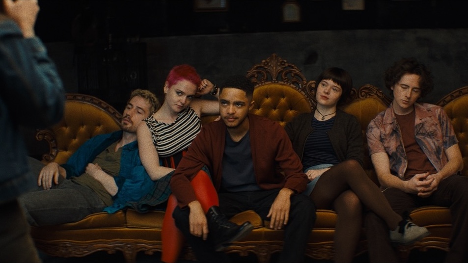 Five people pose on a couch for a photographer