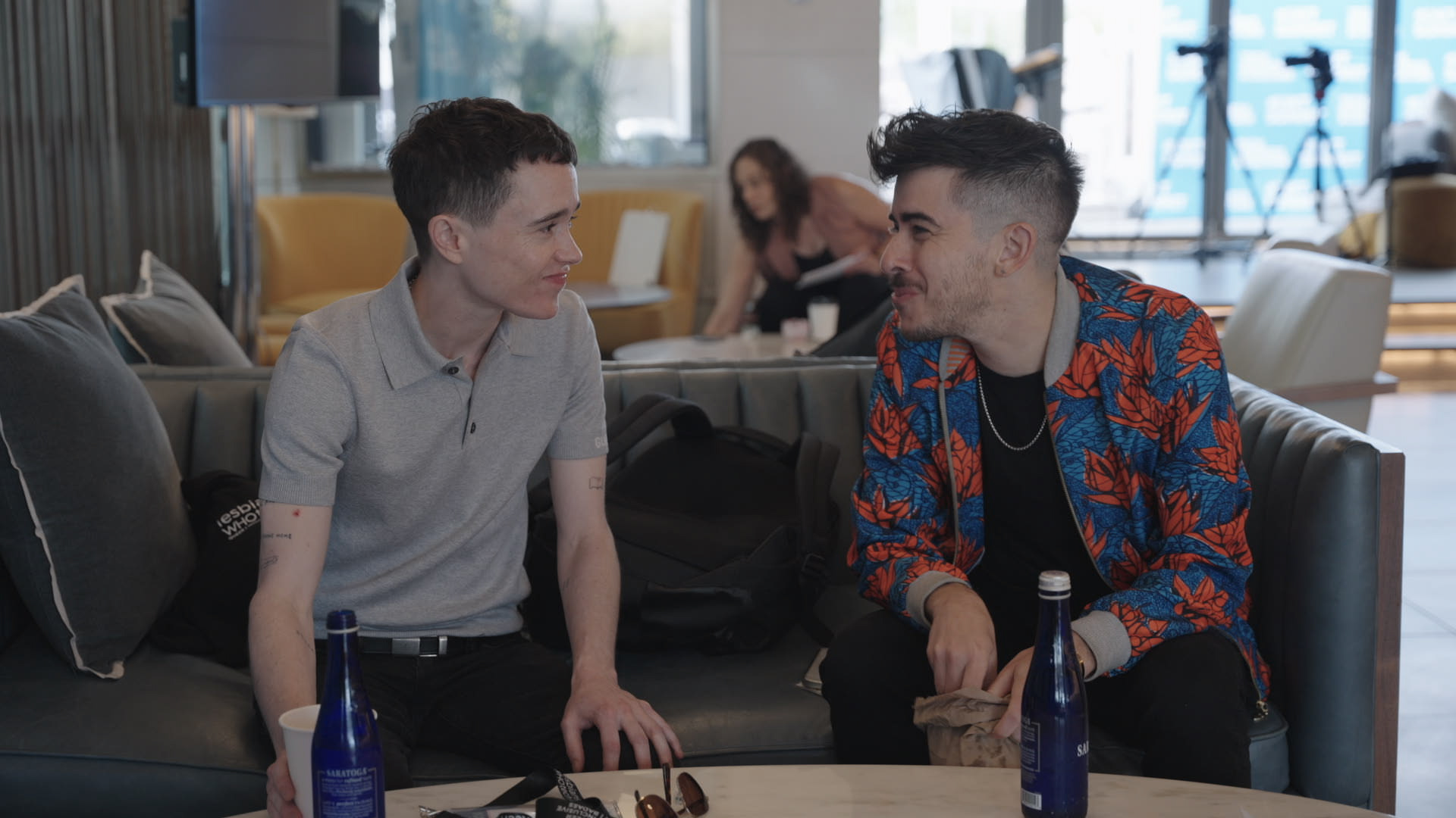 Two trans men sit next to each other on a sofa: one is Elliot Page, the other Chase Strangio